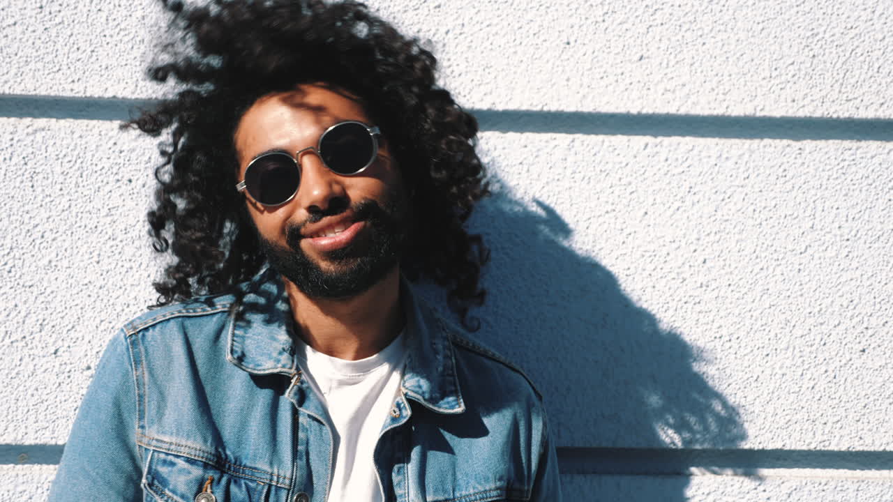 hombre sonriente con chaqueta de vaqueros y gafas de sol