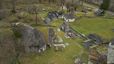 Aerial-drone-zoom-in-shot-over-old-stonewalled-village-houses-in-Cavergno,-District-of-Vallemaggia,-Canton-of-Ticino-in-Switzerland-on-a-cloudy-day