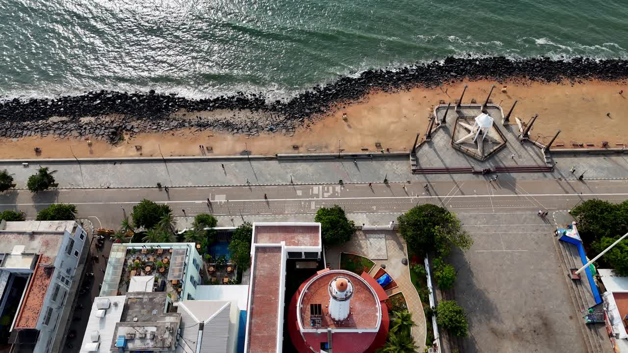 Drohnenaufnahme nähert sich dem Meer von der Stadt aus. Ganz Puducherry und ein Leuchtturm sind in einer frühmorgendlichen Luftaufnahme sichtbar. Die Wellen des Golfs von Bengalen. Größte Gandhi-Statue.