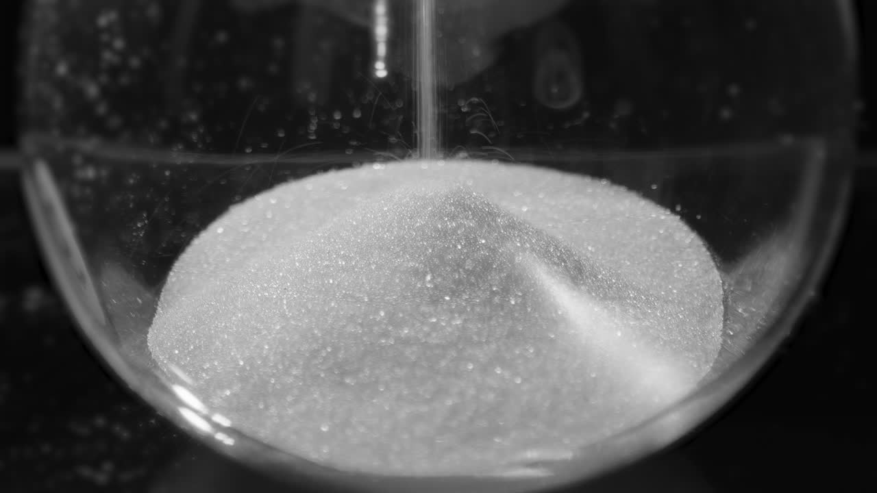 모래시계의 모래방울은 유리 불의 바닥에 떨어집니다. 불포화 클로즈업 뷰