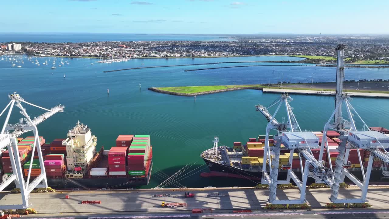 Cranes unloading ships beside stacks of colourful containers at Port Melbourne terminal