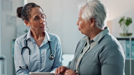 una doctora discutiendo registros médicos con un paciente mayor