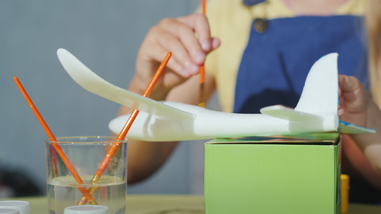 브러시가 있는 어린이의 손은 어린이 4k vide와 함께 게임을 개발하는 항공기의 모델을 페인트합니다.