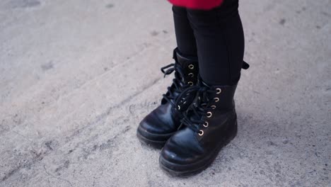 niña con zapatos de cuero de niños negros está de pie en el asfalto