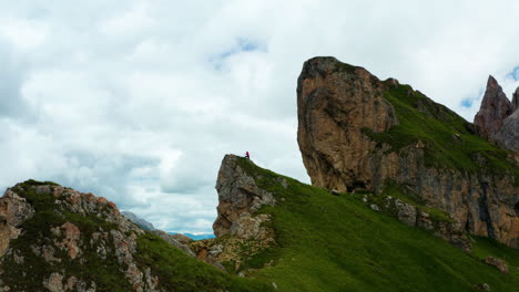 man in distance climbs to edge of seceda cliff in italy's dolomites