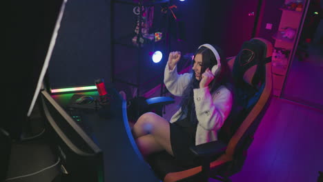 overhead view of focused female gamer with polished nails immersed in intense gameplay, using mouse and keyboard with microphone nearby, surrounded by stylish lighting and neatly organized equipment