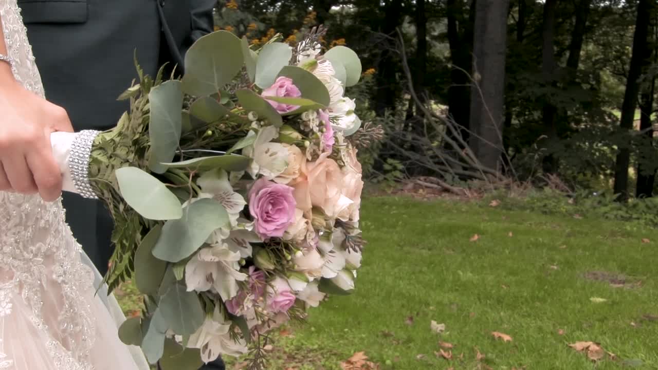 una novia recién casada sosteniendo su ramo de rosas con su novio