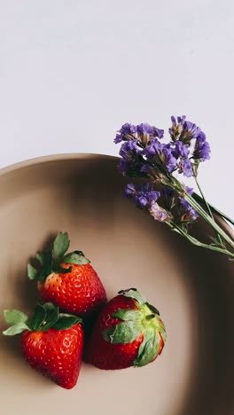 strawberries and flowers on a beige plate