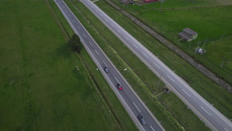 overhead drone clip of quiet two laned road surrounded by grassland and farm buildings