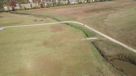ciclista de seguimiento aéreo que viaja a lo largo de la carretera a través de campos agrícolas