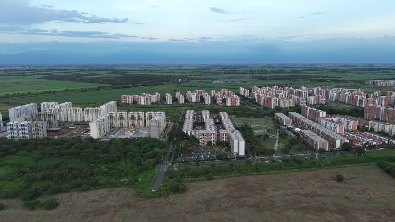 Drone video capturing the expansive residential blocks of Valle del Lili, highlighting urban growth amid lush green landscapes under soft evening light