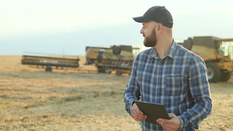 granjero parado en el campo y calculando la cantidad de grano mientras escribe