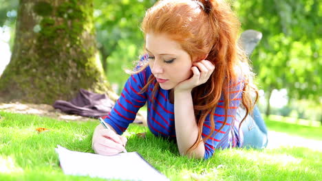 student lying on the grass making notes