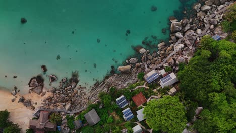 top-down aerial footage of eco resort with solar panels, rocky coastline, sandy beach, and turquoise sea in thailand. perfect for eco-tourism, sustainable travel, nature, and adventure projects.