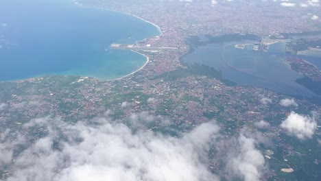 scenic aerial view of balinese landscape and ocean through the clouds in popular tourism destination of bali, indonesia, southeast asia