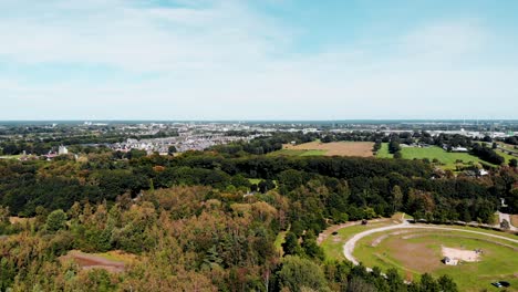 Woodland-park-forest-aerial-view-above-vast-parkland-trees-overlooking-suburban-cityscape