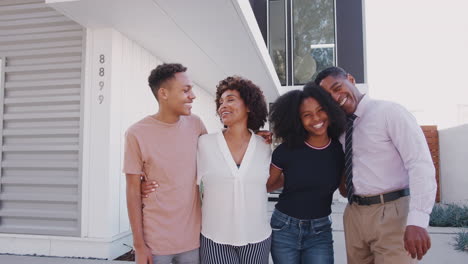 Black-family-stand-looking-to-camera-outside-their-modern-home,-close-up