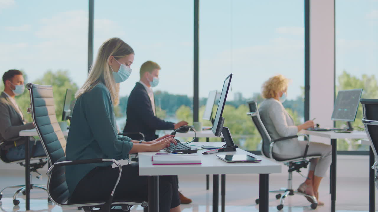 사무실에서 일하는 사업가들이 마스크를 착용하고 있습니다.