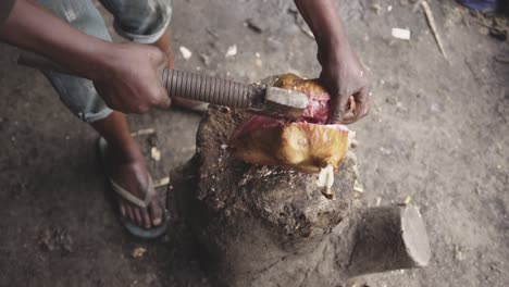 african man cutting meat with axe