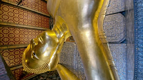 vertical of orbital shot taken from below of a statue of a reclining buddha in a temple in bangkok, thailand