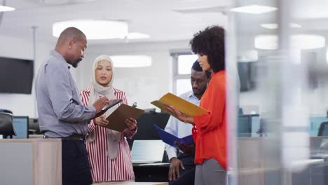 Group-of-diverse-business-people-holding-documents-and-talking-in-office,-slow-motion