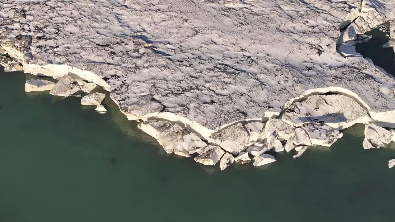 Aerial - icy river edge and fractured snow shelf near Urriðafoss in Iceland