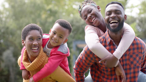 Retrato-De-Felices-Padres-Afroamericanos,-Hijo-E-Hija-Abrazándose-Y-Sonriendo-En-Un-Jardín-Soleado