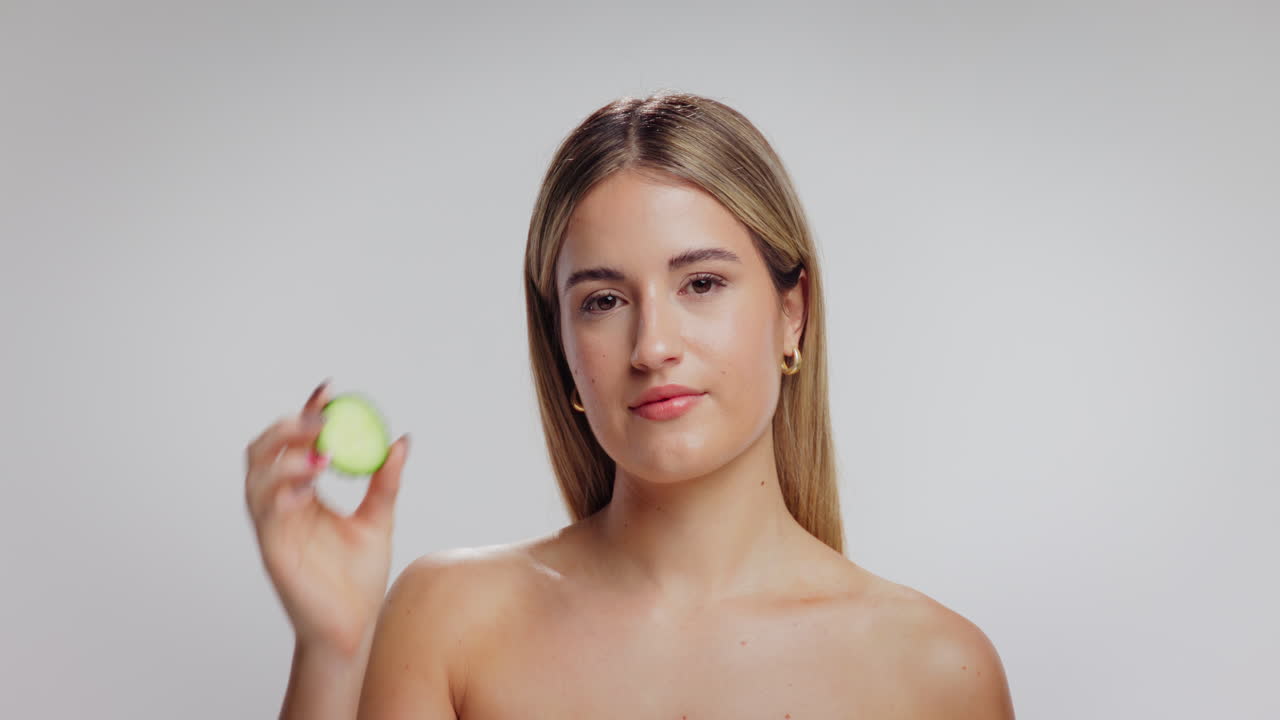Woman covering her eye with cucumber slice