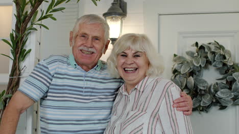 senior couple husband and wife embracing and laughing in porch at home. happy mature family