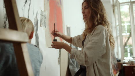 creative woman drawing on canvas. female painter speaking in art studio.