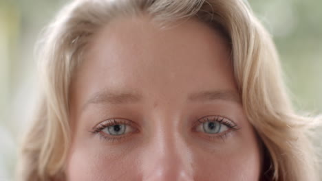 portrait close up of blonde caucasian woman opening blue eyes and smiling, slow motion