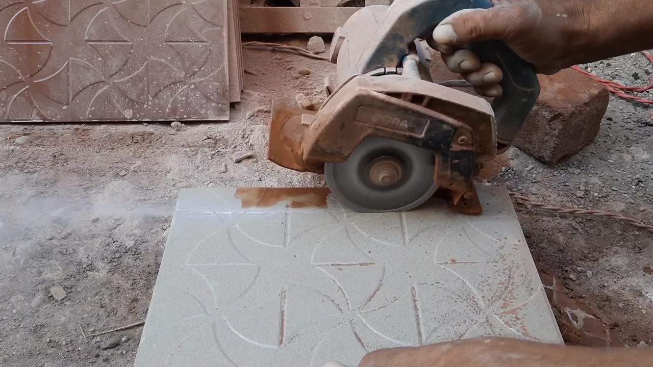 worker cutting a tile using an angle grinder at the construction site, Ceramic tile cuts by a circular saw with water cooling