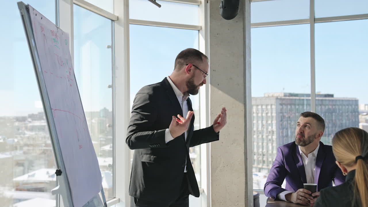Businessman in suit talking to business people colleagues or partners sitting at conference table. Leader discussing work at morning team meeting.