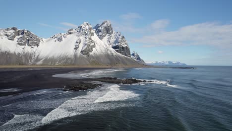 Volando-Sobre-La-Costa-Con-Impresionantes-Montañas-Vestrahorn-Cubiertas-De-Nieve-Que-Se-Elevan-Desde-La-Playa