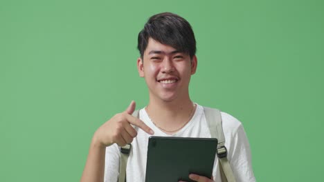 close up of asian man student using tablet and direct fingers to tablet on green screen studio