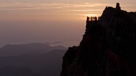 Silhouette-of-hikers-at-sunrise-crowd-viewpoint-Ninho-da-Manta,-near-Pico-do-Arieiro-at-popular-Madeira-trail,-drone-view