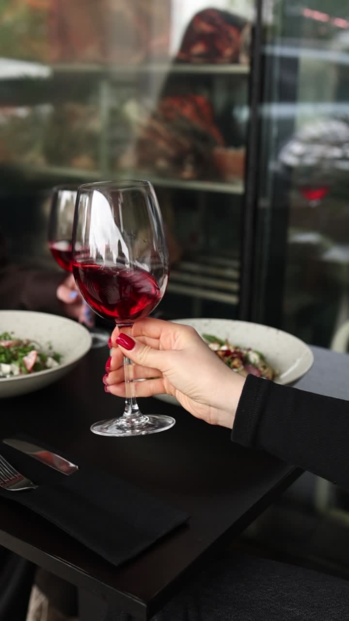 mujer disfrutando de vino rojo en un restaurante con ensalada