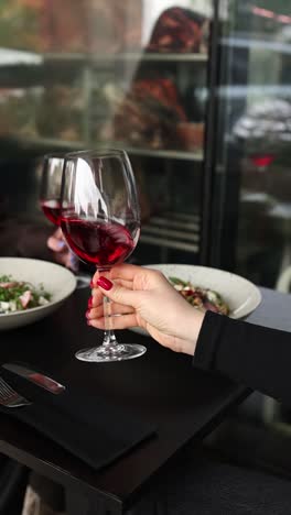 woman enjoying red wine at a restaurant with salad