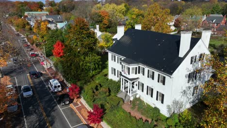 white colonial house surrounded by fall foliage in small town america