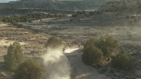 dirt bike riders run through dusty trail in colorado