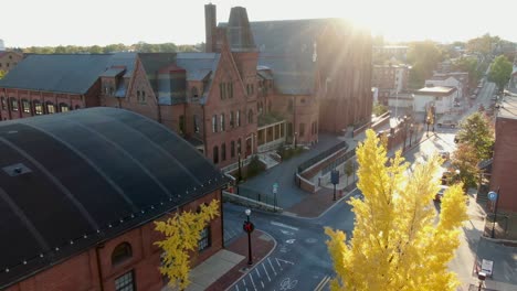 hermoso árbol de arce amarillo en la ciudad iluminado por el sol, iglesia histórica y mercado en lancaster pa usa durante el otoño, corona navideña colgada en un poste de luz