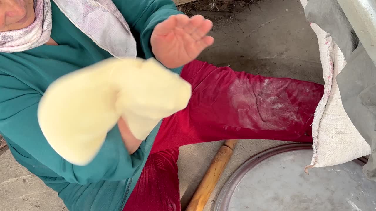 숙련 된  ⁇ 집은 밀가루 반죽을 사용하여 평평한  ⁇ 을  ⁇ 고 튜브 나무 불 오븐 땅 점토 뜨거운 실린더 모양 중동 음식 페르시아 지역 여성 시골 지역에서 녹색 드레스 빨간