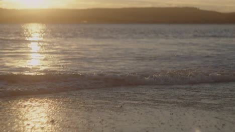 una hermosa puesta de sol dorada sobre las olas de la playa en devon, reino unido