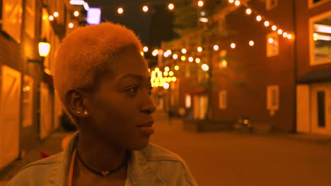 a trendy, young woman looking at lights in the street and smiling