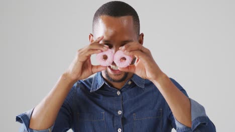 Video-of-biracial-man-holding-donuts-over-white-background