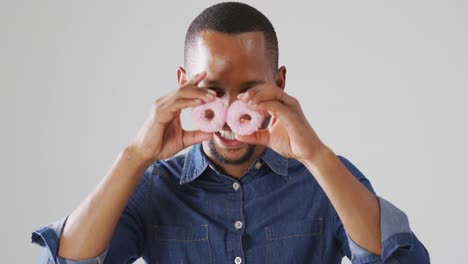 video de un hombre biracial sosteniendo rosquillas sobre un fondo blanco