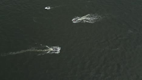 two motorboats speeding across open water with visible wakes , aerial view