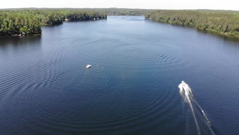 boat circling around people swimming in the lake who are preparing to water ski