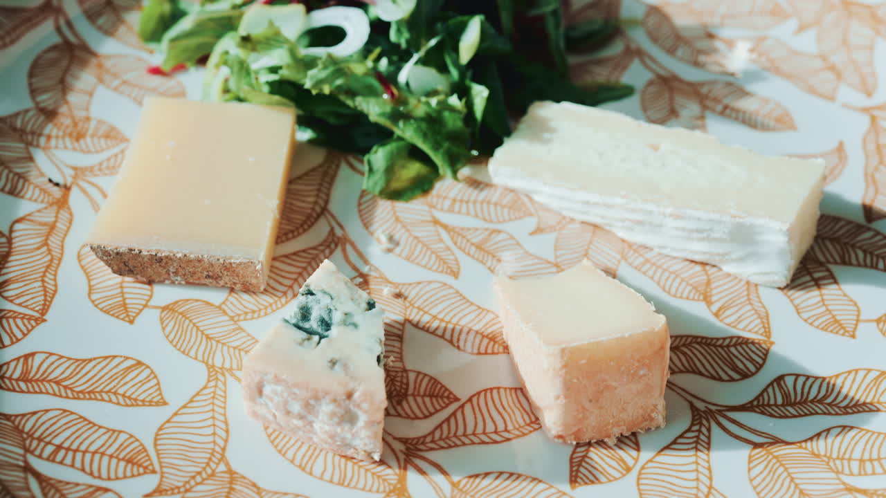 Close up of a fork and knife slicing into a piece of cheese from the platter