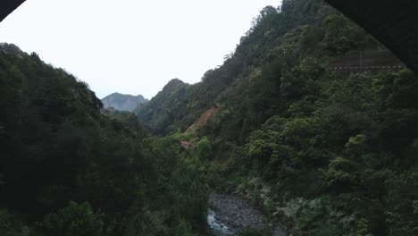 drone view of the hills and river in madeira from under the bridge, portugal